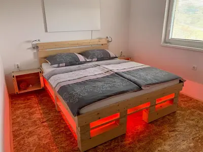 a bedroom with a wooden bed with red lights on it at Holiday House Zlačka Gorca in Pristava pri Mestinju