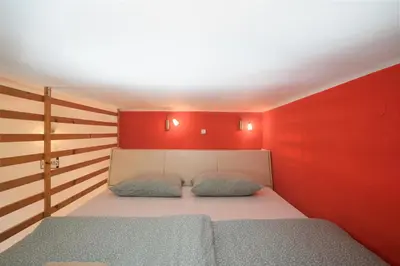 a bedroom with red walls and a bed with two pillows at Urban view apartment with free parking in Ljubljana