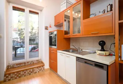 a kitchen with wooden cabinets and a sink and a window at Urban view apartment with free parking in Ljubljana