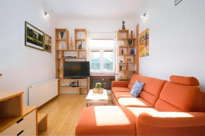 a living room with an orange couch and a television at Urban view apartment with free parking in Ljubljana