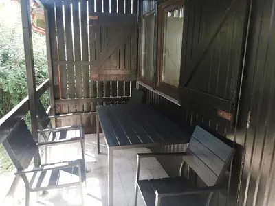 a porch with two chairs and a table and a bench at Počitniška HIŠKA POLOVNIK in Bovec