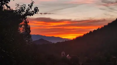 a sunset in the mountains with a house in the foreground at Rock Apartments in Bohinjska Bela
