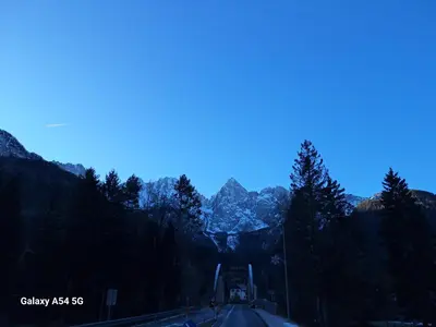 a road in the mountains with trees and mountains at Apartma Aurora in Kranjska Gora