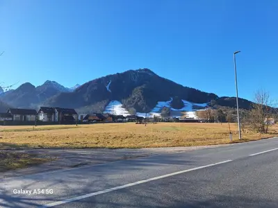 an empty road with a field and mountains in the background at Apartma Aurora in Kranjska Gora