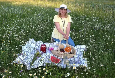 a woman sitting in a field with a basket of food at Apartment Sneznik in Stari Trg pri Ložu