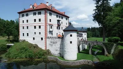 a large castle with a bridge over a body of water at Apartment Sneznik in Stari Trg pri Ložu