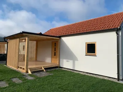 a small white house with a wooden deck at Ribiška vasica - Fishermen's Village in Radeče
