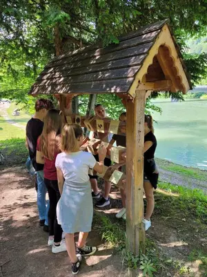 a group of people standing around a wooden structure at Ribiška vasica - Fishermen's Village in Radeče
