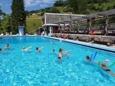 a group of people swimming in a swimming pool at Ribiška vasica - Fishermen's Village in Radeče