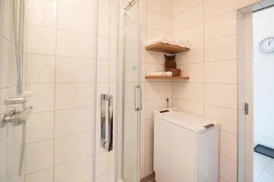 a bathroom with a shower and a washing machine at Apple tree apartment in Bled
