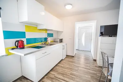 a kitchen with white cabinets and a table and chairs at CUDERLAND STUDIO KURNIK in Kobarid