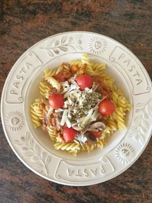 a plate of pasta with tomatoes and mushrooms on a table at B&B Margarita in Cerkovna