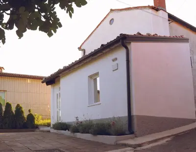a small white house with a roof at APARTMA KMETIJA ROVAN in Vrhpolje