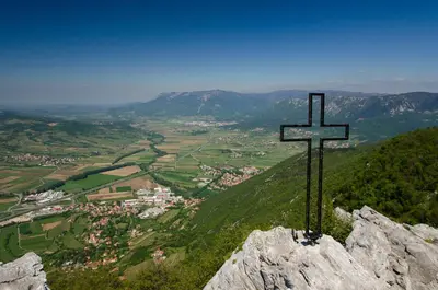 a cross on top of a mountain overlooking a town at APARTMA KMETIJA ROVAN in Vrhpolje