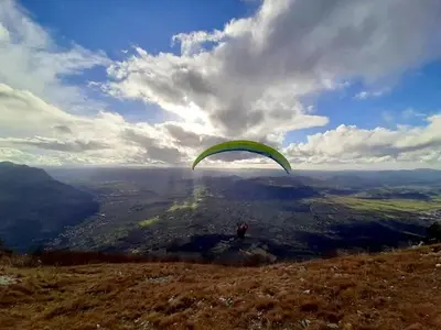 a person flying a parachute on top of a hill at APARTMA KMETIJA ROVAN in Vrhpolje