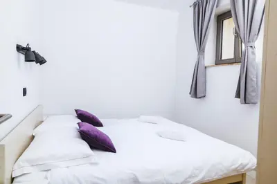 a white bed with purple pillows in a room at Roner Resort in Plavje