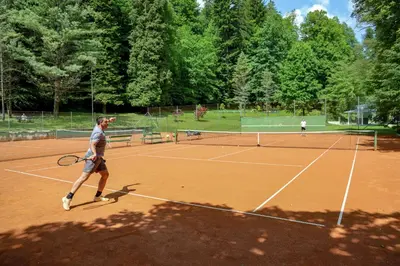a man is playing tennis on a tennis court at Spa Suite Dobrna - Terme Dobrna in Dobrna