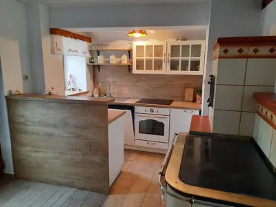 a kitchen with white cabinets and a wooden floor at Vineyard cottage Klobčar in Semič