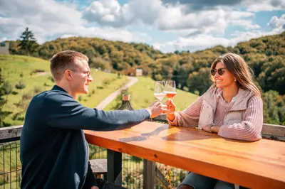 a man and woman sitting at a table with wine glasses at Nesting Resort - Homestead SONČNI RAJ in Maribor
