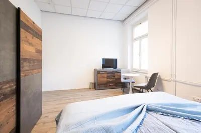 a bedroom with a bed and a desk and a tv at Epicenter - rooms & terrace in Ljubljana