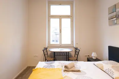 a bedroom with a bed and a table and a window at Epicenter - rooms & terrace in Ljubljana