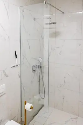 a shower with a glass door in a bathroom at Woody - comfy apartment in Šiška in Ljubljana