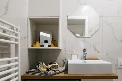 a white bathroom with a sink and a mirror at Woody - comfy apartment in Šiška in Ljubljana