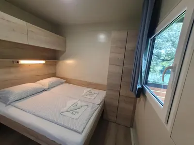 a small bed in a small room with a window at GM House, mobile house near Kolpa river in Metlika