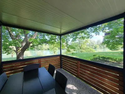 a screened in porch with a table and chairs at GM House, mobile house near Kolpa river in Metlika