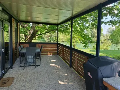 a screened in porch with a table and chairs and a dog at GM House, mobile house near Kolpa river in Metlika