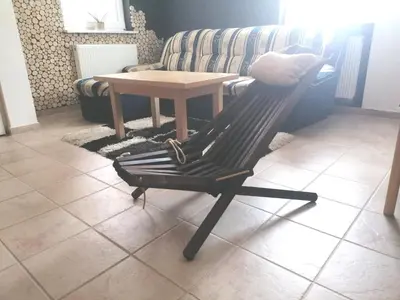 a chair in a living room with a table and a couch at Rogla - Apartma ROŽLE in Vitanje