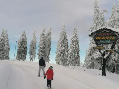 a couple of people walking down a snow covered road at Rogla - Apartma ROŽLE in Vitanje
