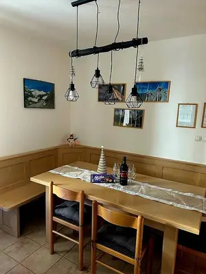 a dining room table with two chairs and lights at Rogla - Apartma ROŽLE in Vitanje