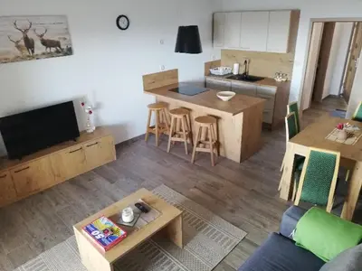 a living room with a couch and a table and a kitchen at Apartmaji Hočka Koča in Pohorje