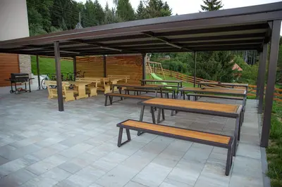 a group of picnic tables and benches under a pavilion at Apartmaji Hočka Koča in Pohorje