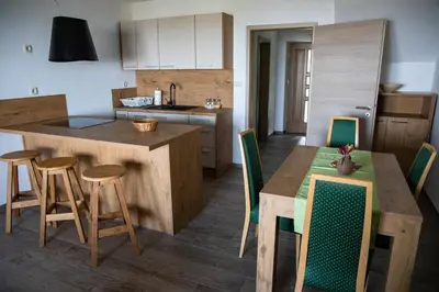 a kitchen with a wooden table and chairs and a kitchen with a counter at Apartmaji Hočka Koča in Pohorje