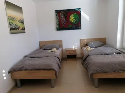 a bedroom with two twin beds and a painting on the wall at BLATNIKOV HRAM in Dvor