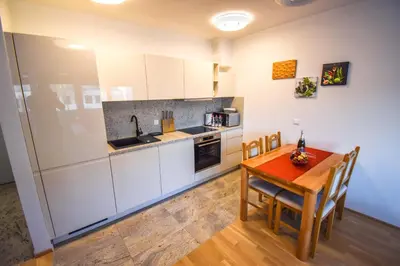 a kitchen with white cabinets and a wooden table at City Centre Lux in Maribor
