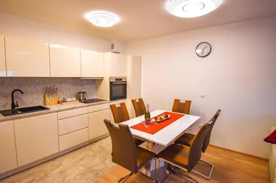 a kitchen with a table and chairs and a clock on the wall at City Centre Lux in Maribor