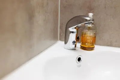 a bottle of alcohol sitting on a bathroom sink at Hotel Murat in Ptuj