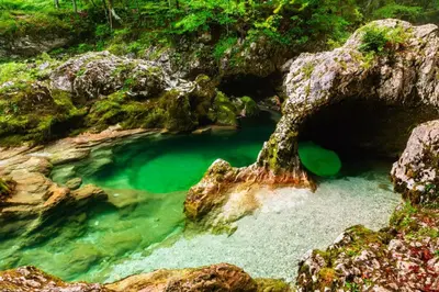 a pool of emerald green water in a cave at Villa Pokljuka in Zgornje Gorje