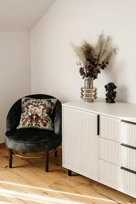 a black chair sitting next to a white cabinet with a vase on it at Pr Kopač in Brezovica