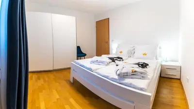 a bedroom with a white bed with white sheets at Bella Mura Blue Apartment in Moravske Toplice