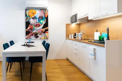 a kitchen with a table and a painting of a woman at Bella Mura Blue Apartment in Moravske Toplice