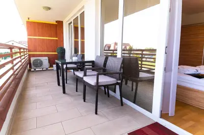 a balcony with a table and chairs and a bed at Bella Mura Blue Apartment in Moravske Toplice