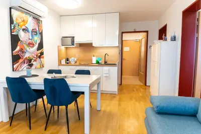 a kitchen and living room with a table and chairs at Bella Mura Blue Apartment in Moravske Toplice