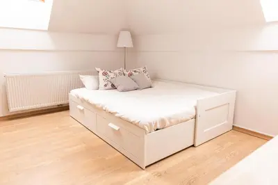 a small bedroom with a white bed with pillows at Vigorous Bled Apartment in Bled