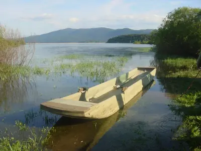 a boat sitting in the water on a lake at Apartments Vrdjan in Cerknica