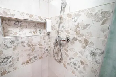 a shower in a bathroom with flowers on the wall at Guesthouse Močivnik in Okroglice