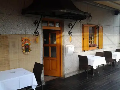 a restaurant with white tables and chairs and a wooden door at Guest House Arvaj in Kranj